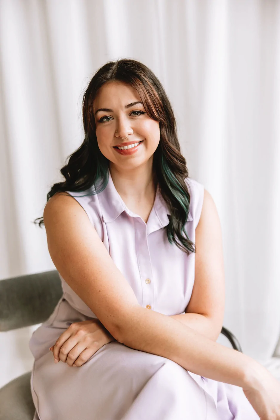 Dietitian Rachel Green is a woman with long brown hair sits on a chair, smiling, wearing a sleeveless light purple dress, with a white curtain in the background. Ohio