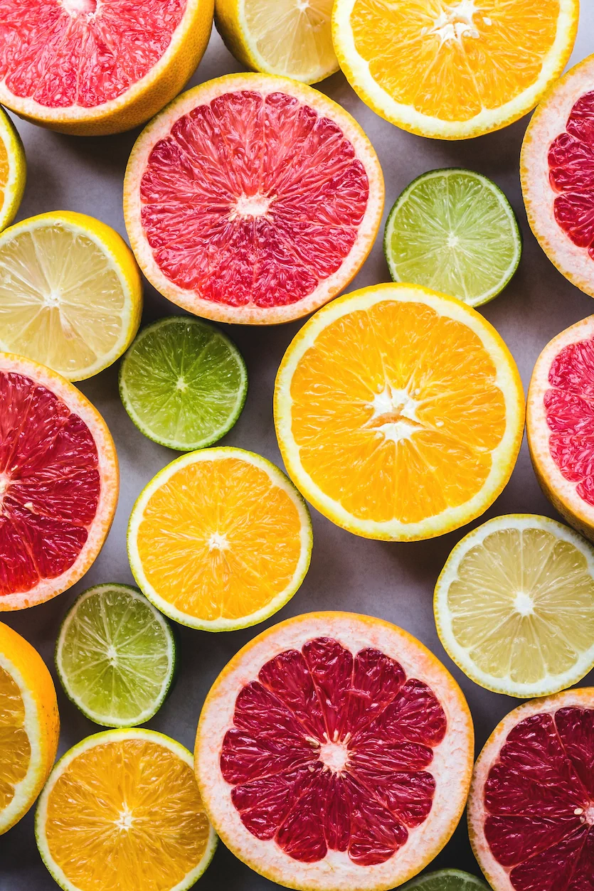 Assorted citrus fruits, including grapefruits, oranges, lemons, and limes, cut in half and arranged on a flat surface. representing Vitality Nutrition with Rachel Green in Ohio